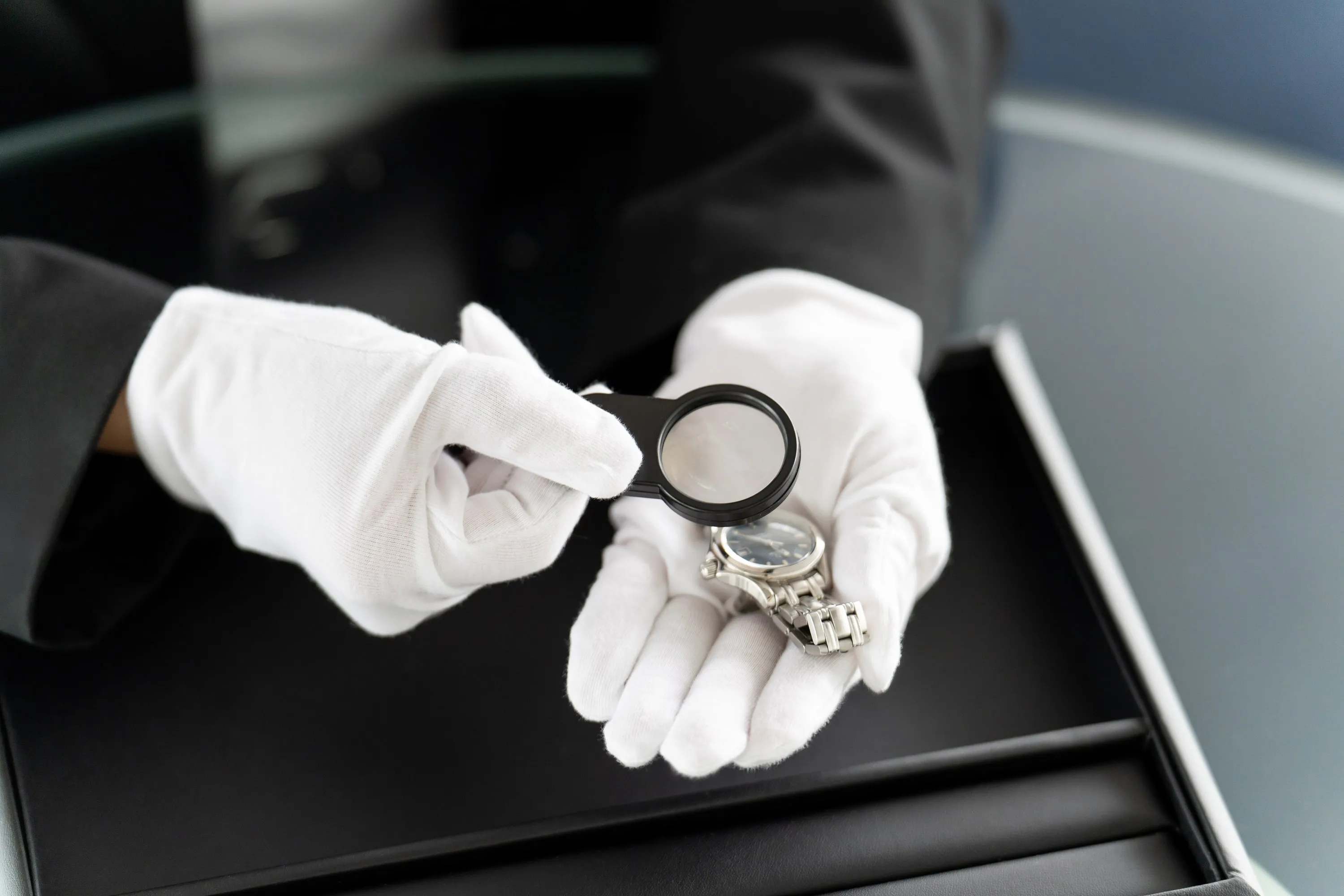 Uhrenbewertung mit Lupe und weißen Handschuhen – sorgfältige Prüfung bei Juwelier Böhnel
